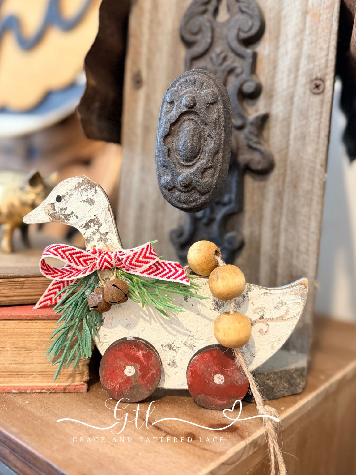 Vintage pull toy goose Christmas ornament with red wheels, greenery, bells, and a red patterned bow